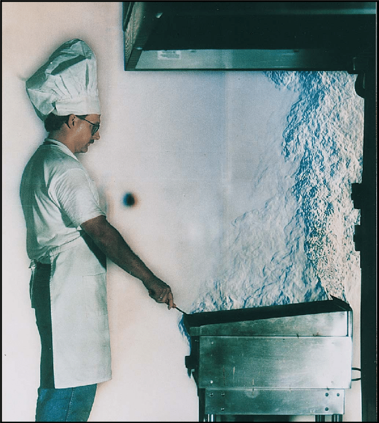 A commercial kitchen griddle and exhaust hood in use with cooking fumes made visible by the schlieren technique.