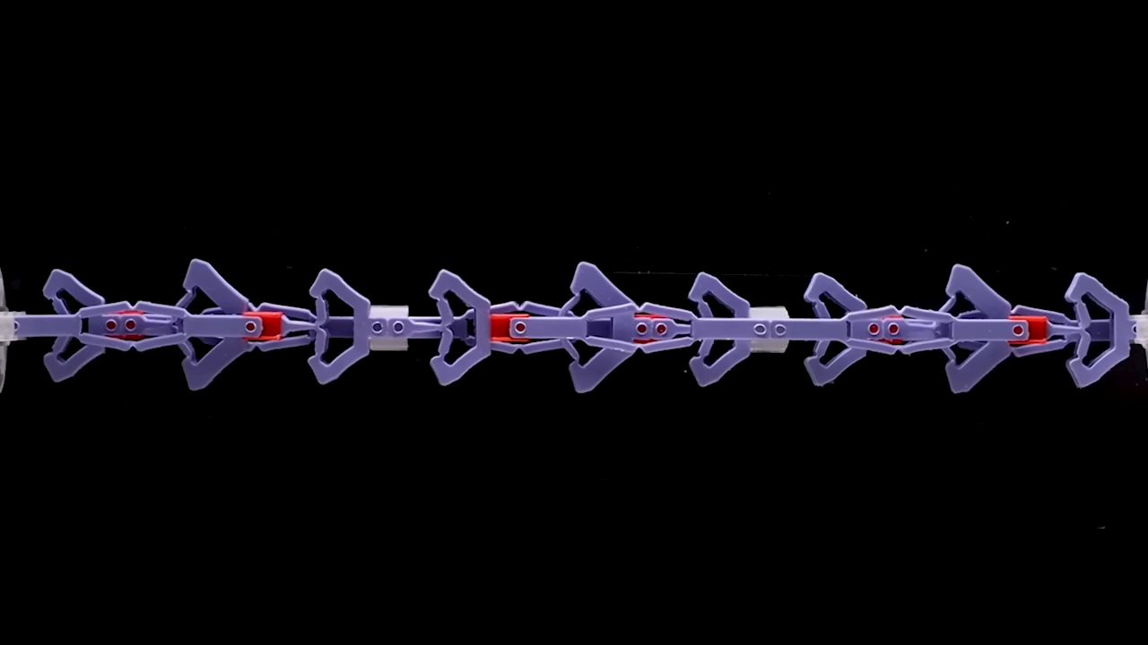 Series of purple and red mechanisms are stretched from left to right. Almost like arrows pointing right.