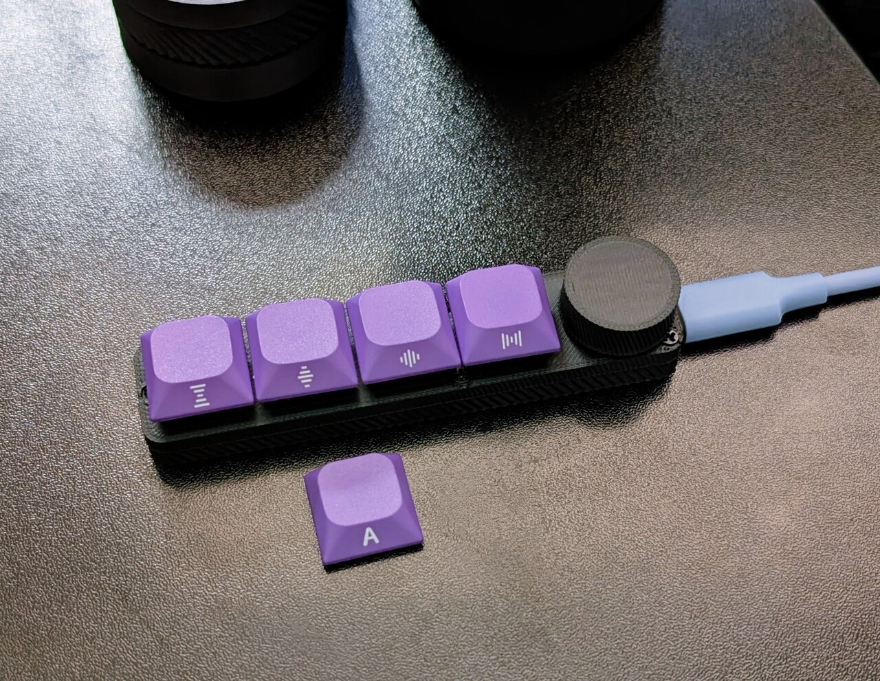 An in-line media control bar with four purple-capped key switch buttons and a knob.
