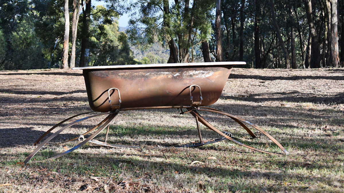 Rusty bathtub outdoors on equally rusty car springs