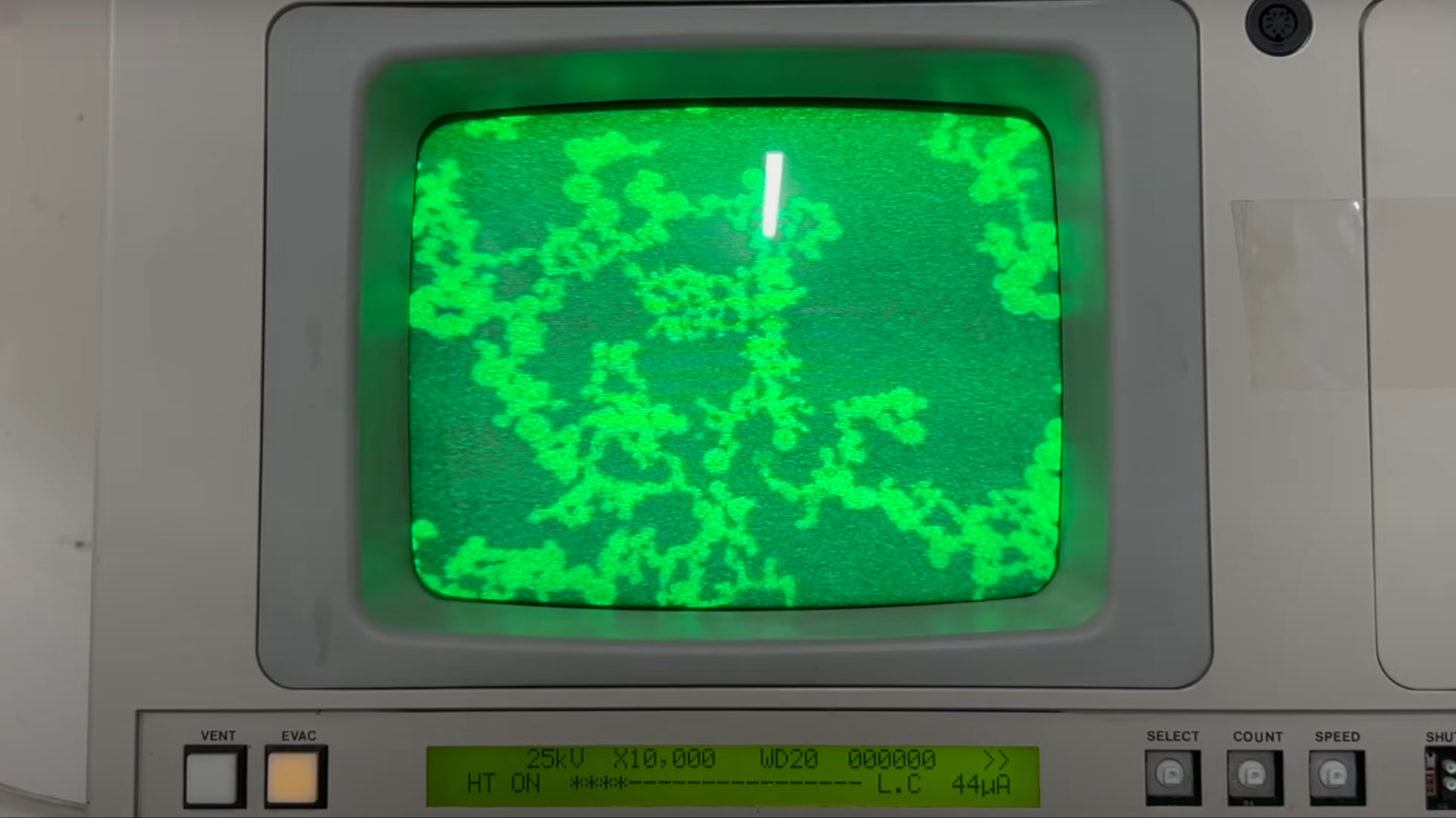 The green CRT display of a scanning-electron microscope is shown, displaying small particles.