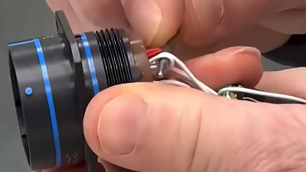 Fingers installing a service loop in a wire in a connector