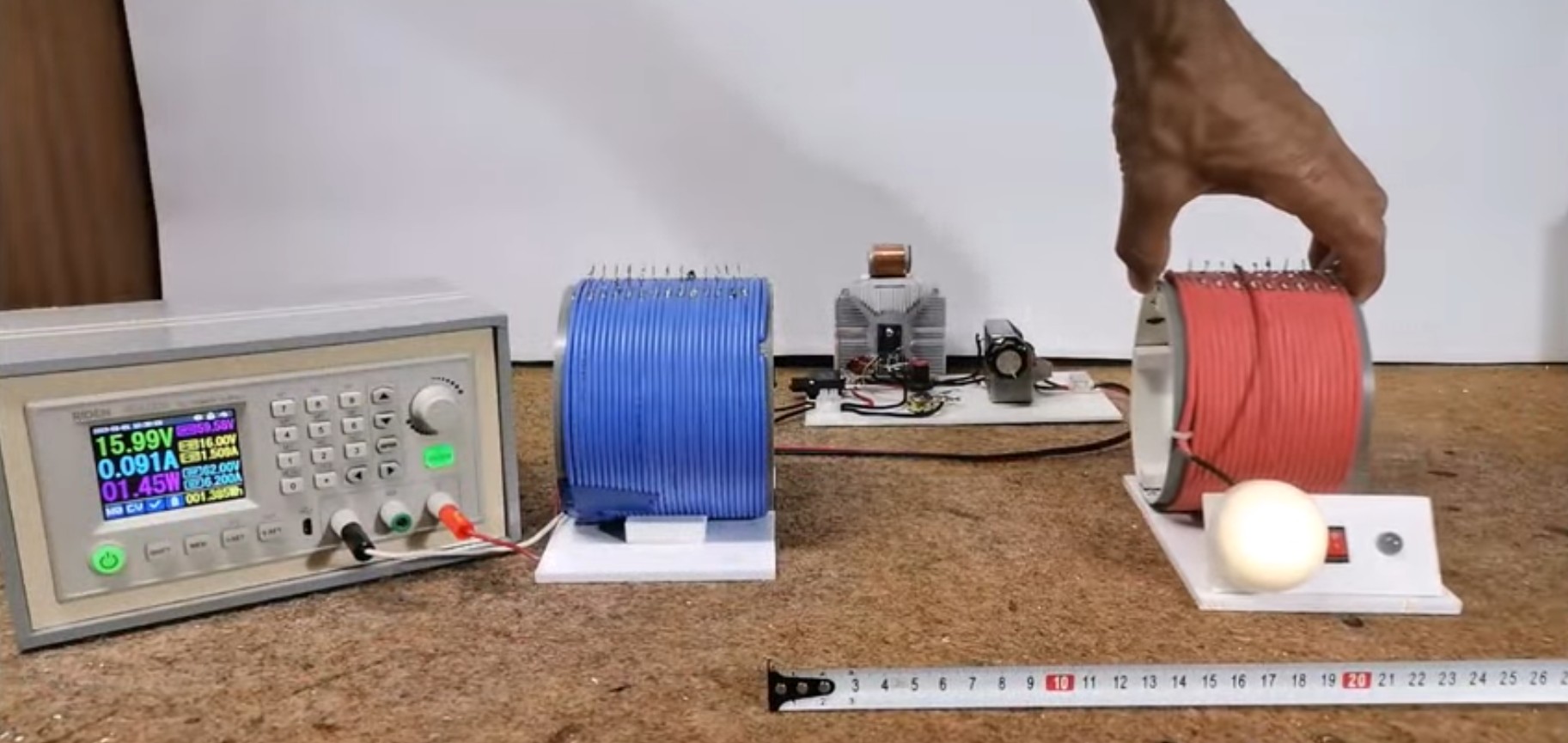 A photo of a the power supply, distribution board, and primary and secondary windings on a bench top.