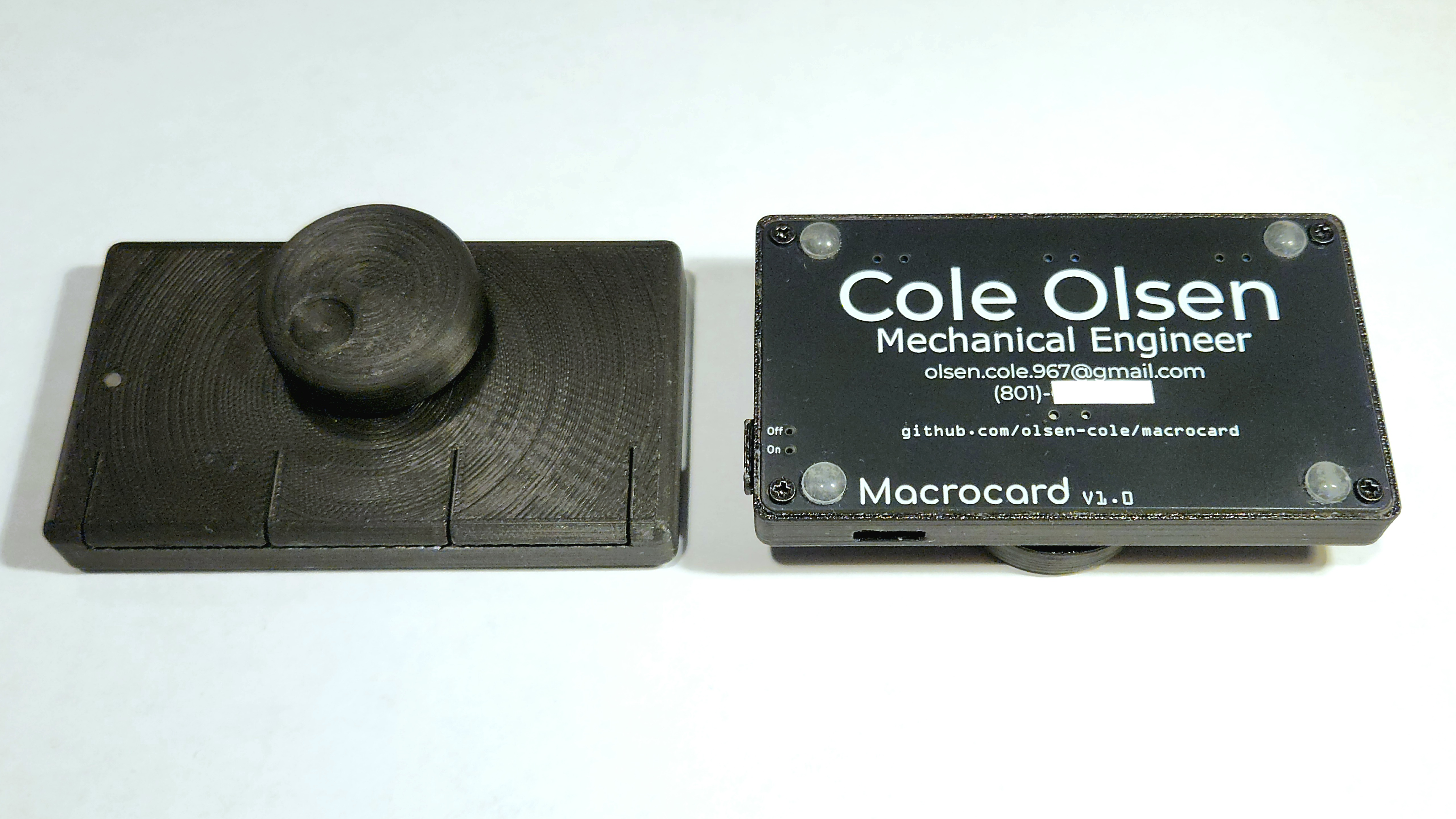 Two sides of a business-card shaped device are shown. On the left, it’s clear that the device is about half a centimeter thick, with a large scroll wheel visible in the center. The device cover is 3D-printed in black plastic, and has cutouts to mark where three buttons ar. On the right, the underside of the device is visible. It is a black PCB, with white text giving contact information.