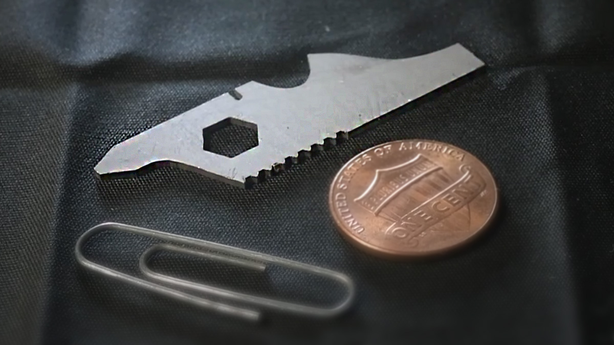 Close up of a DIY minimalist EDC multitool, a penny, and a paperclip