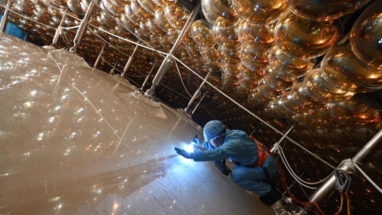 A worker inspects JUNO's acrylic sphere under the watching eye of PMTs