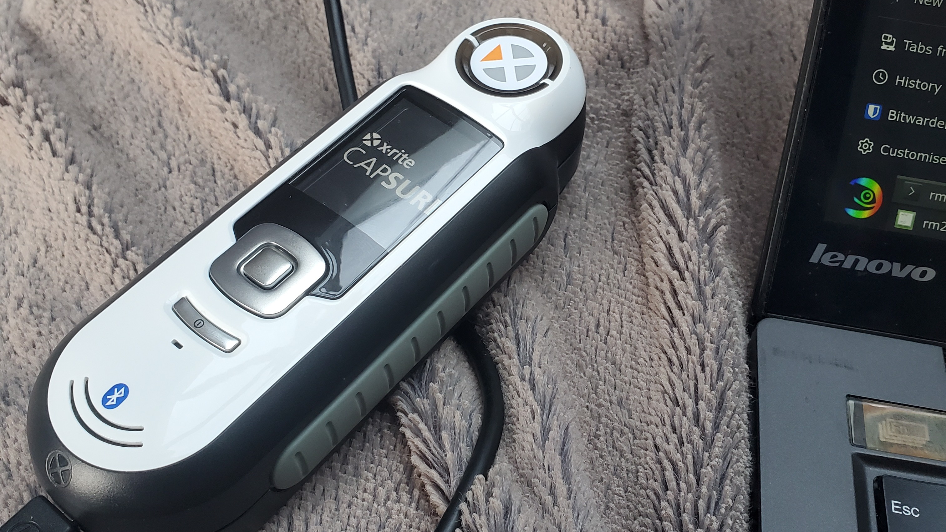 A thick, rectangular device with rounded corners is shown, with a small screen in the upper half, above a set of selection buttons.