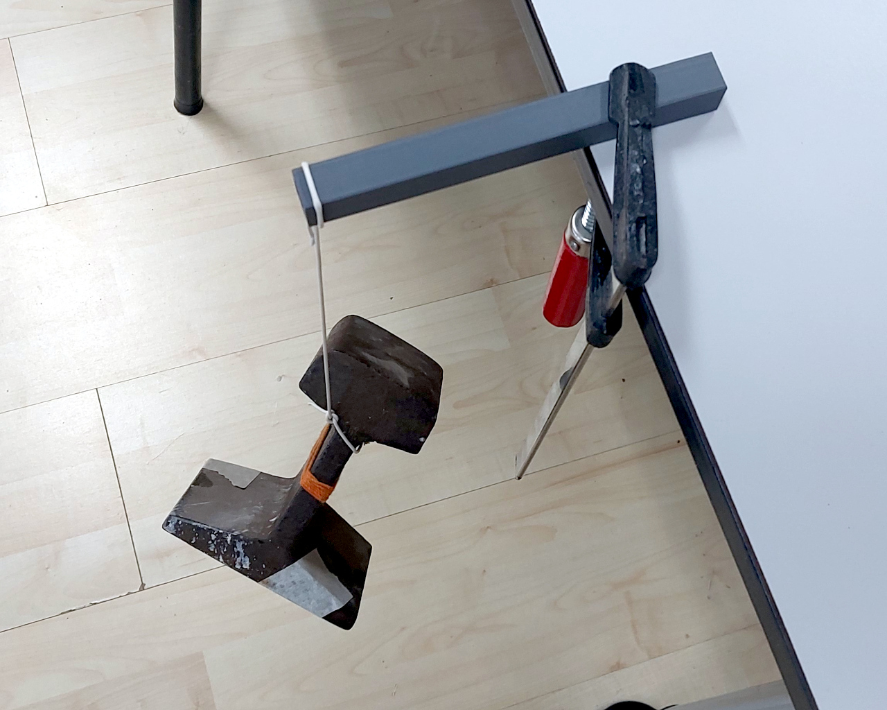 A 3d printed box section clamped to a table, with a piece of steel rail suspended from it